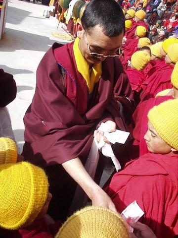 Monk distributing monetary gifts to young monks at the Spituk Festival, 2003.