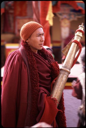 Monk carrying a Tibetan great horn, or dungchen, at the Spituk monastery winter festival.