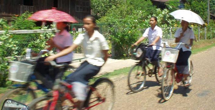 Girls bicycling around the village of Champasak, southern Laos.