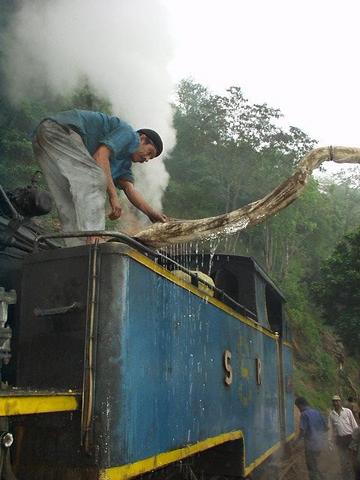 Man filling the Ooty train's locomotive with water.