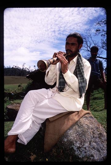 Man playing a flute in the hills near Ooty, Tamil Nadu. These men were herders of water buffalo and played the flute to pass the time in the fields.