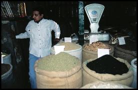 A merchant in his shop with his bags of spices.