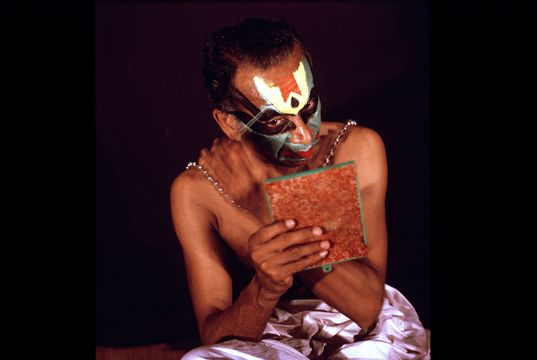 Kathakali dancer putting on his makeup.