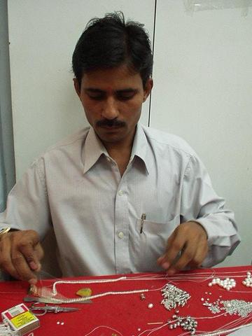 Man stringing pearls for Preethi.