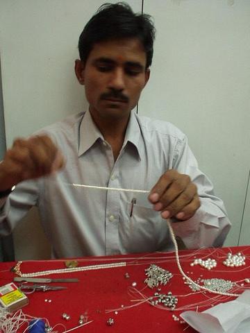 Man stringing pearls into a necklace, Hyderabad.