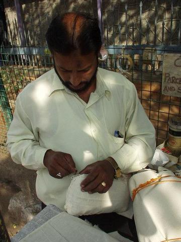 Man sewing up a package, Hyderabad post office.