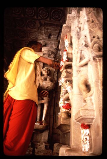 A jain holy man cleaning sculptures in the temple at Osiyan. He is wearing a mask to prevent him inhaling any insects, as part of a devout Jain practice of not harming any living thing.